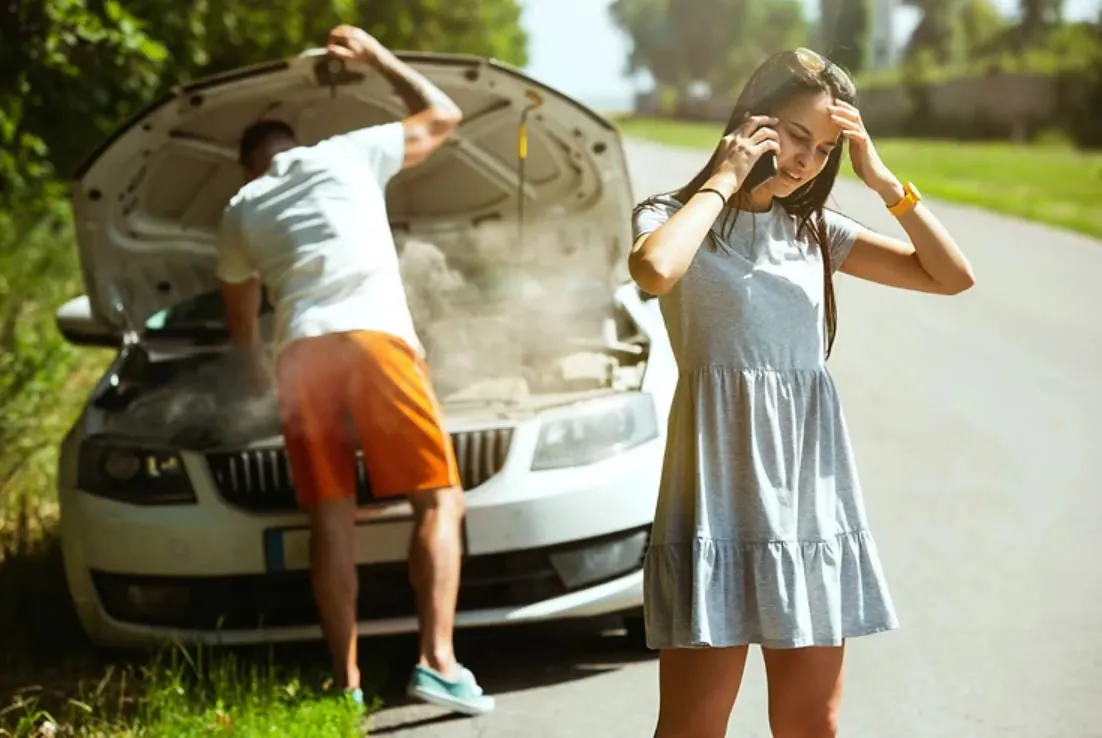 couple broken down by side of road woman on phone